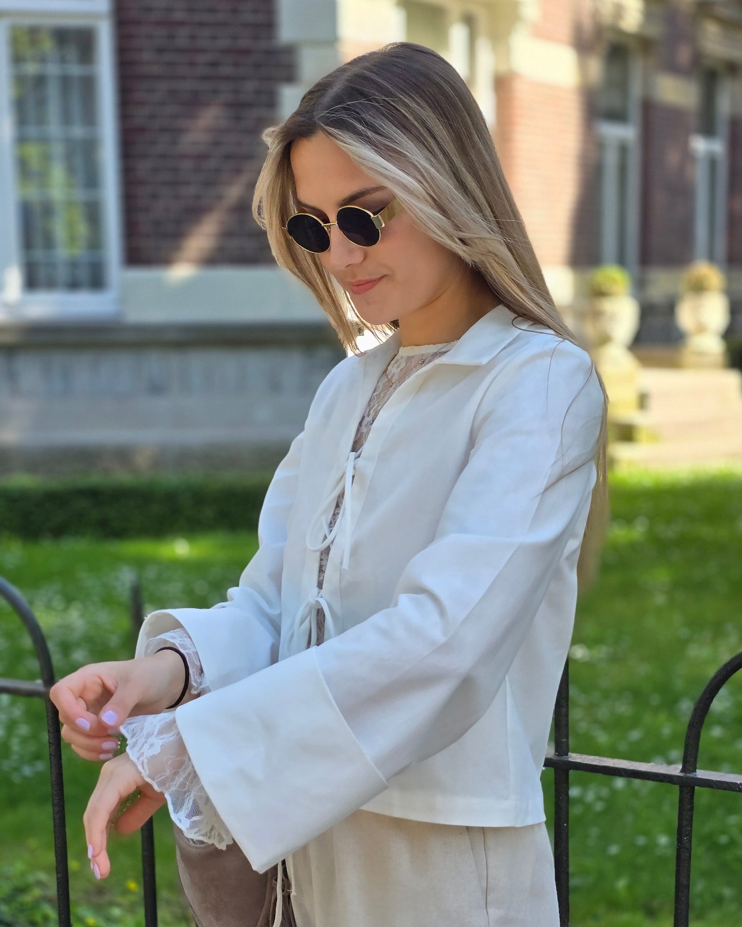 Blouse blanche en coton-lin à manches longues avec poignets larges. Coupe droite légèrement courte avec des liens à nouer à l’avant.