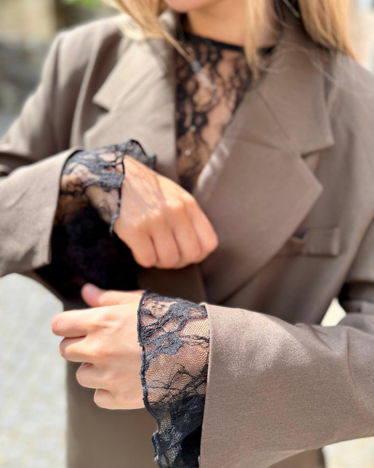 Blouse noire en dentelles légère et transparente. Coupe moulante avec des longues manches évasées et une dentelle florale.