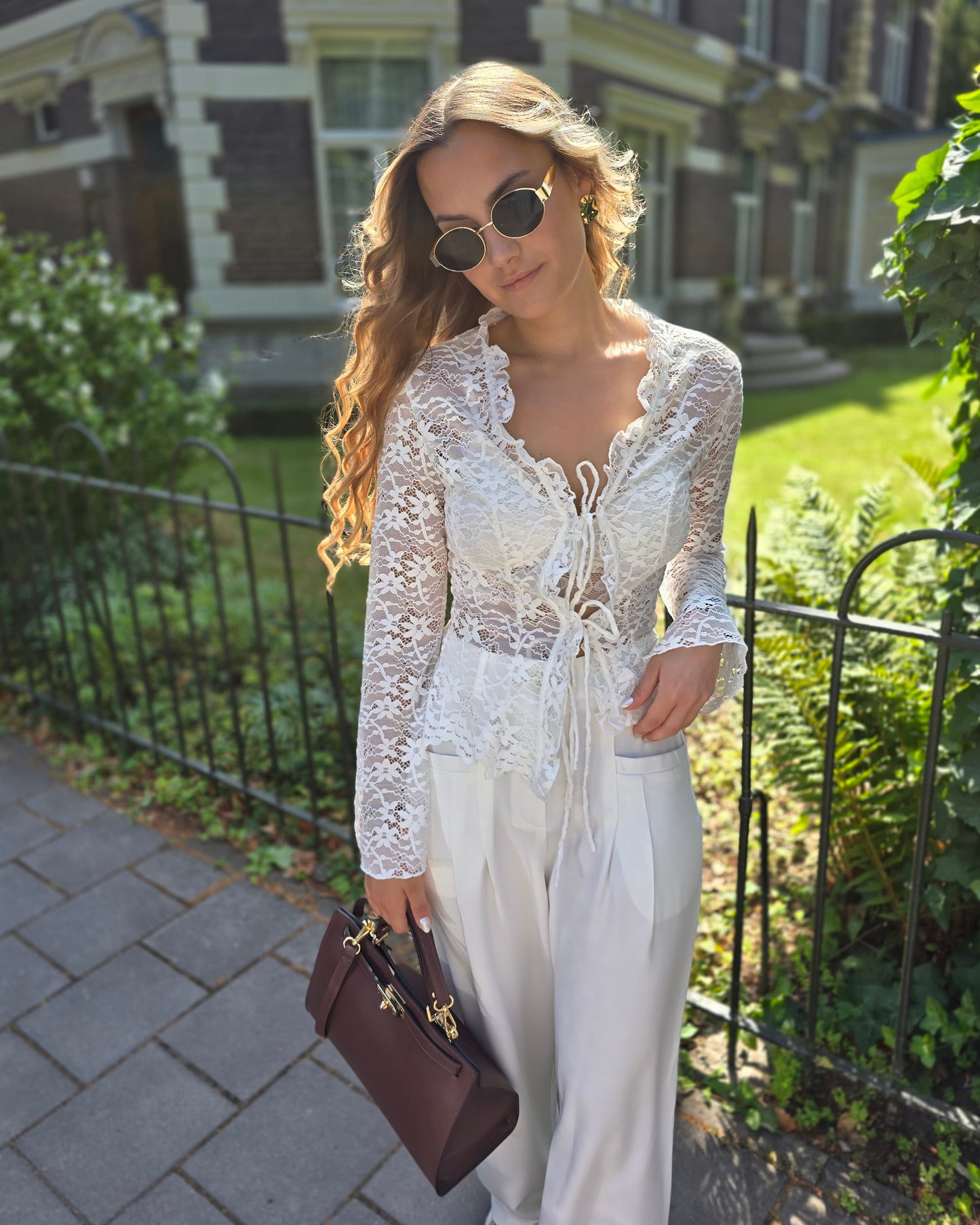 Blouse à dentelle blanche manches longues. S’attache avec deux petites cordelettes.