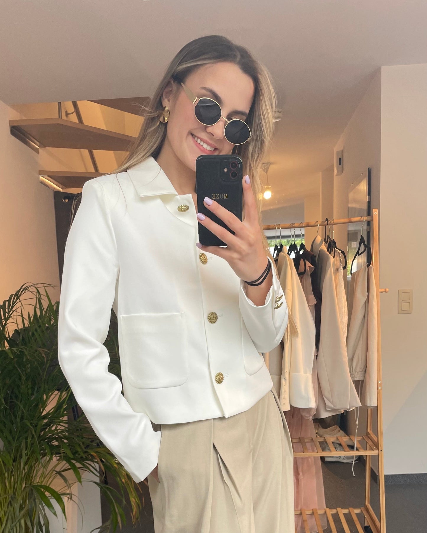 Veste blanche tailleur. Coupe droite légèrement cintrée. Fermeture avec des boutons dorés gravés et deux grandes poches à l’avant.