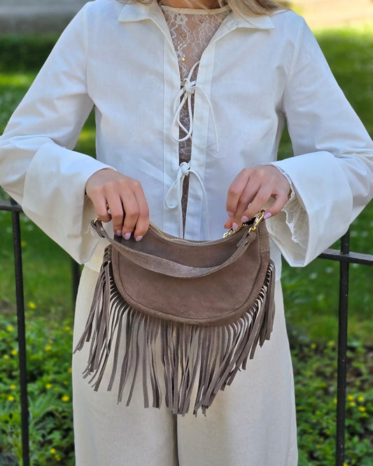 Sac à main en forme demi-lune 100% cuir de vachette. Avec des longues franges sur le bas et une bandoulière ajustable. Finitions dorées. 