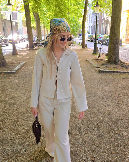 Blouse beige en coton-lin à manches longues avec poignets larges. Coupe droite légèrement courte avec des liens à nouer à l’avant. 