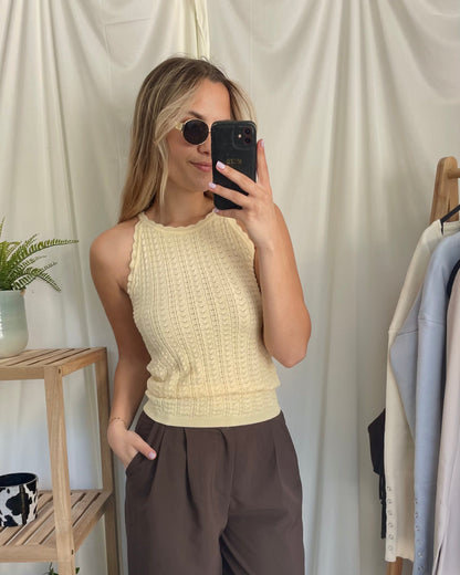 Top jaune pastel en maille texturée. Col légèrement montant avec une longueur au-dessus des hanches. 