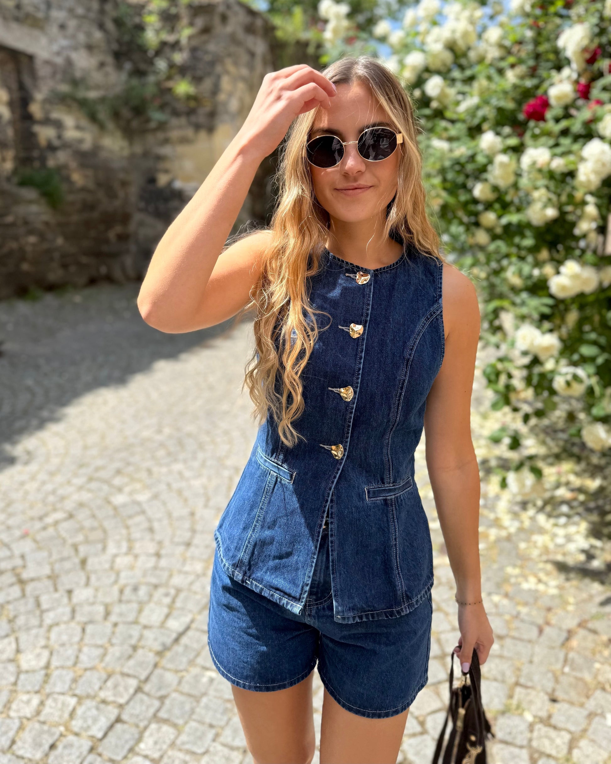 Top sans manche en denim cintré. Avec des boutons dorés et une encolure ronde. 