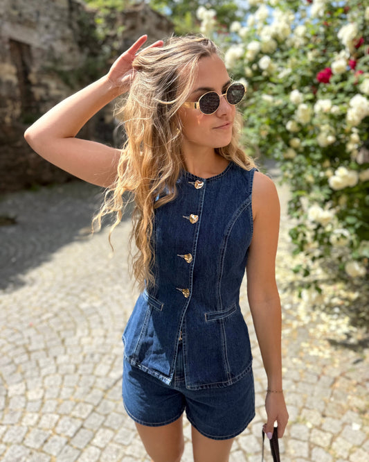 Top sans manche en denim cintré. Avec des boutons dorés et une encolure ronde. 