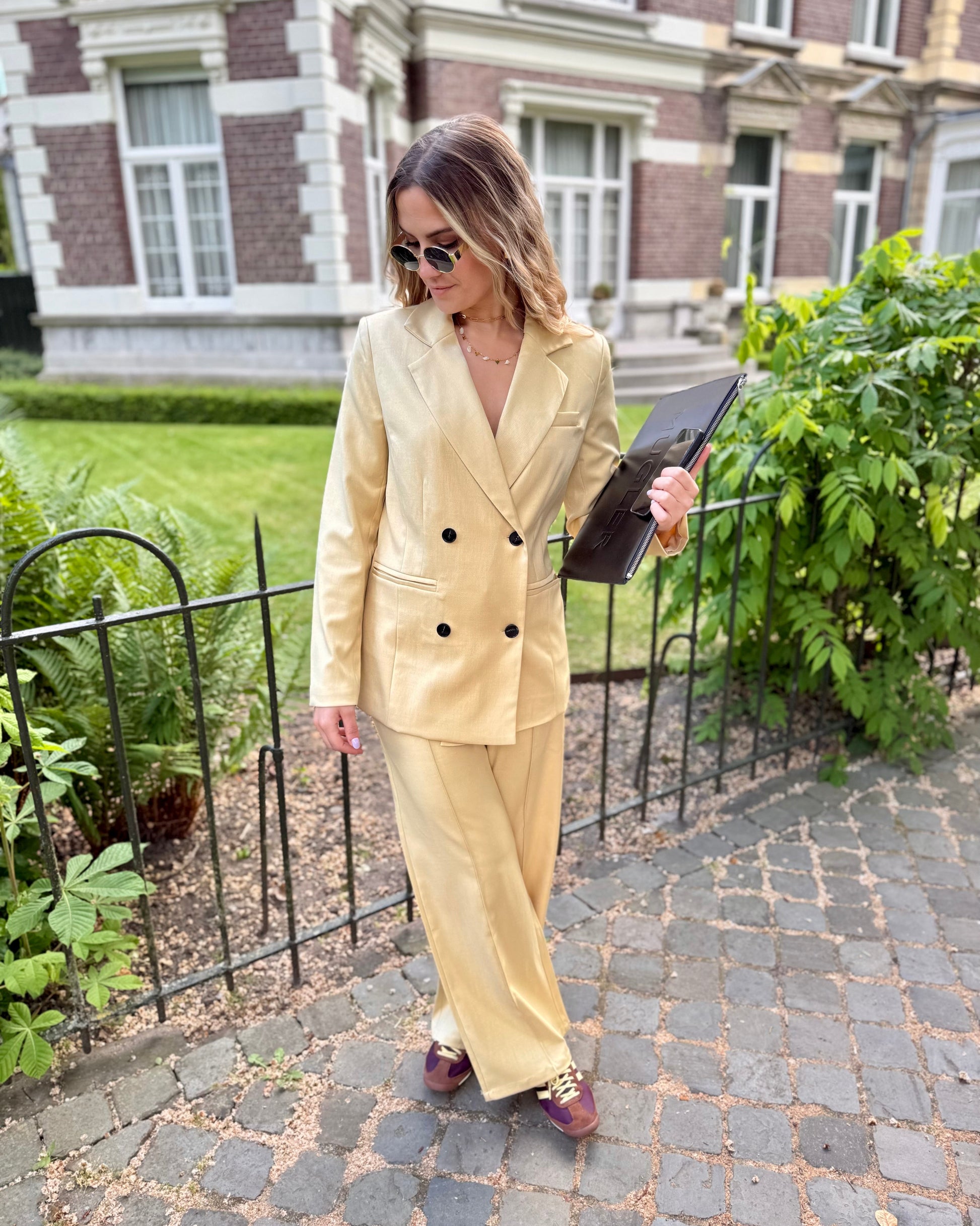 Veste blazer jaune pastel avec le pantalon assorti. Double boutonnage noir. Épaules structurées. 