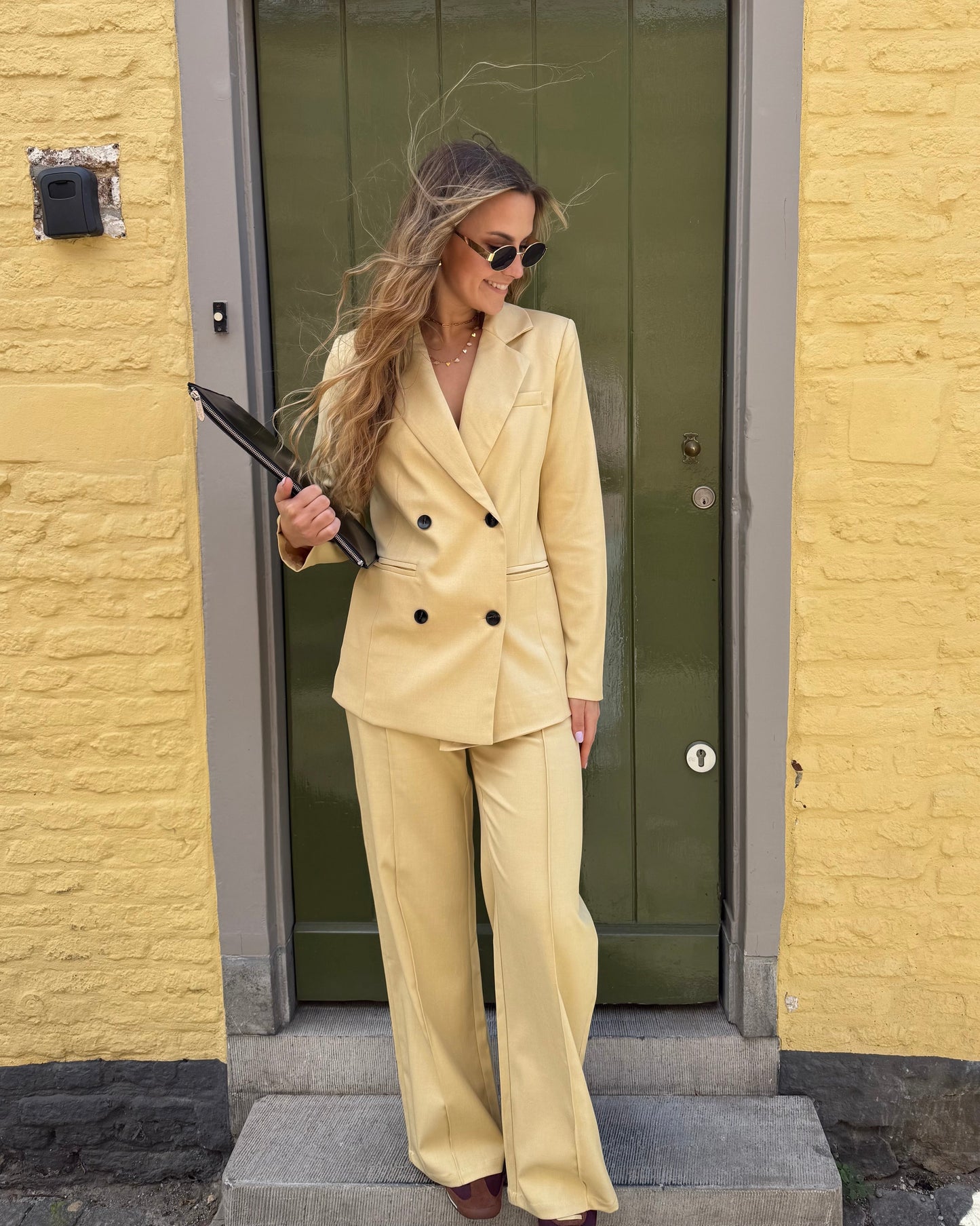 Veste blazer jaune pastel avec le pantalon assorti. Double boutonnage noir. Épaules structurées. 