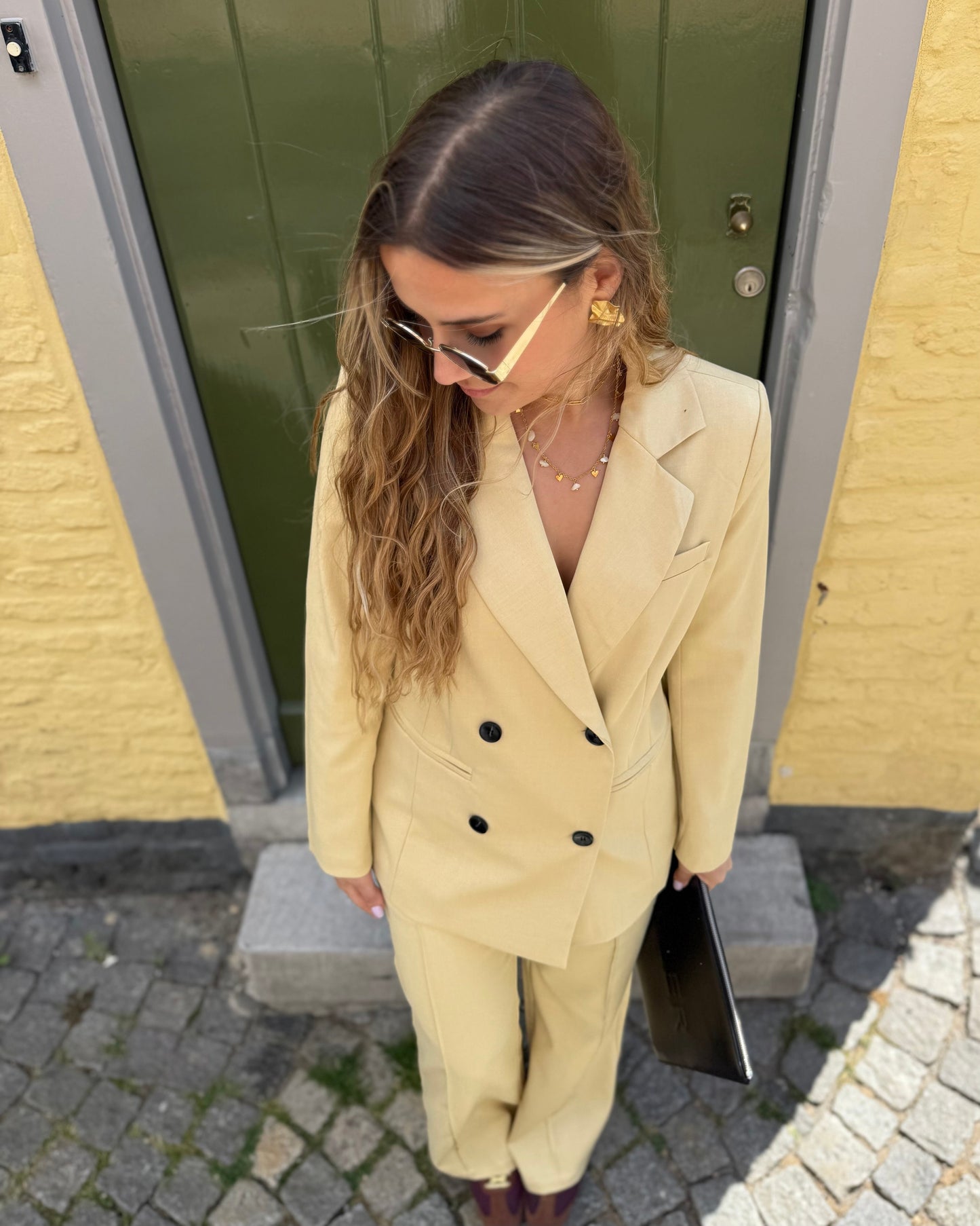 Veste blazer jaune pastel avec le pantalon assorti. Double boutonnage noir. Épaules structurées. 