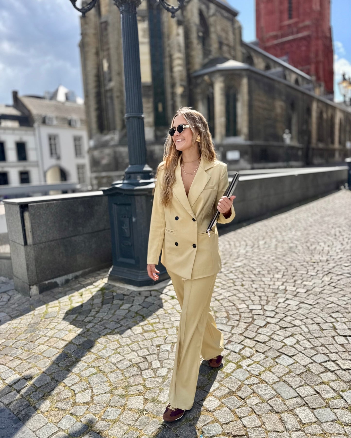 Veste blazer jaune pastel avec le pantalon assorti. Double boutonnage noir. Épaules structurées.