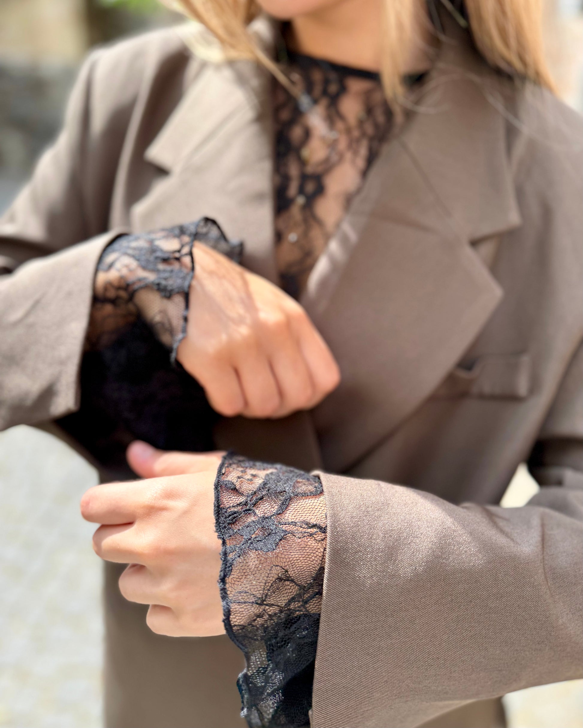 Blouse noire en dentelles légère et transparente. Coupe moulante avec des longues manches évasées et une dentelle florale. 