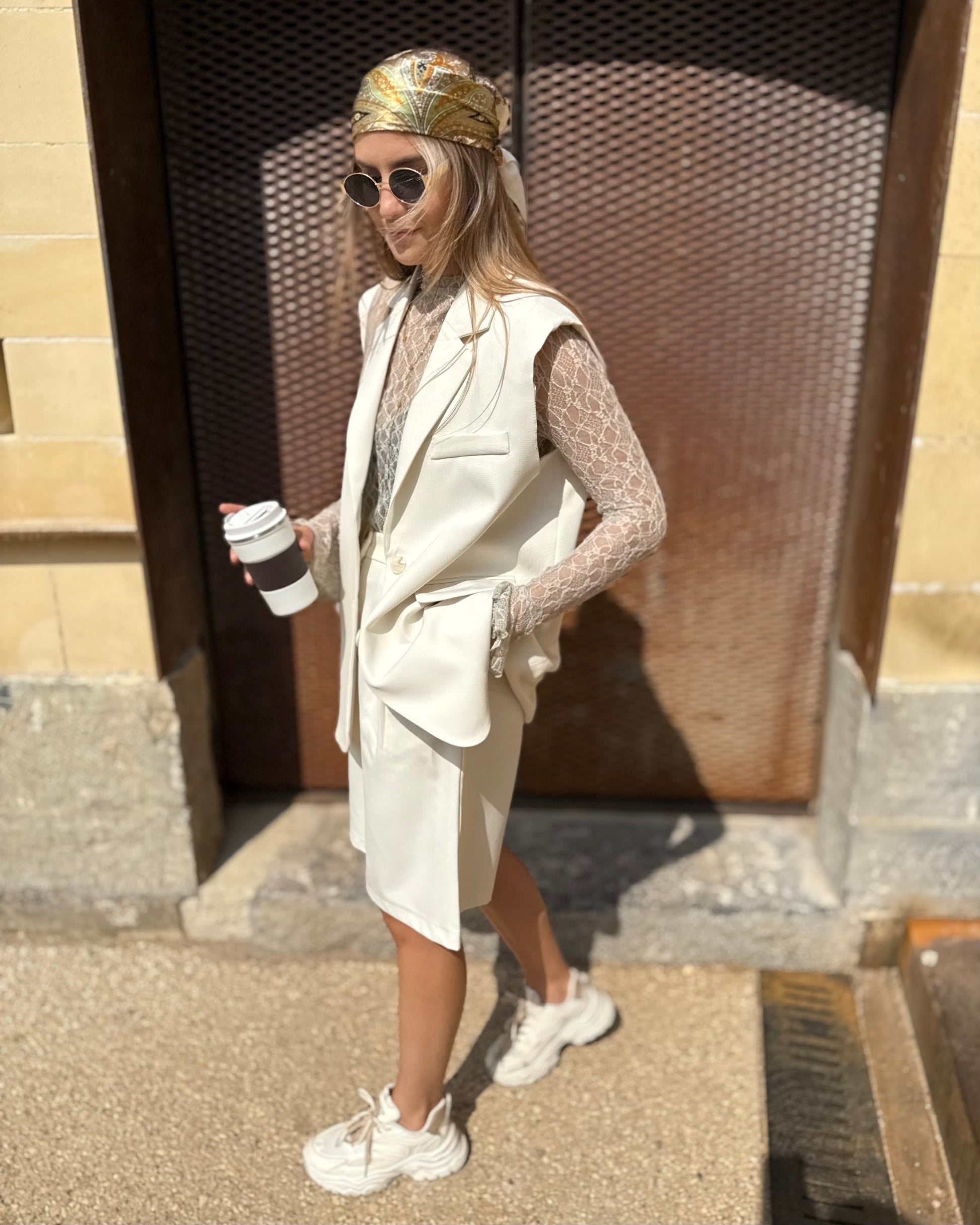 Blazer sans manches couleur écru. Deux fausses poches devant et fente à l’arrière. 