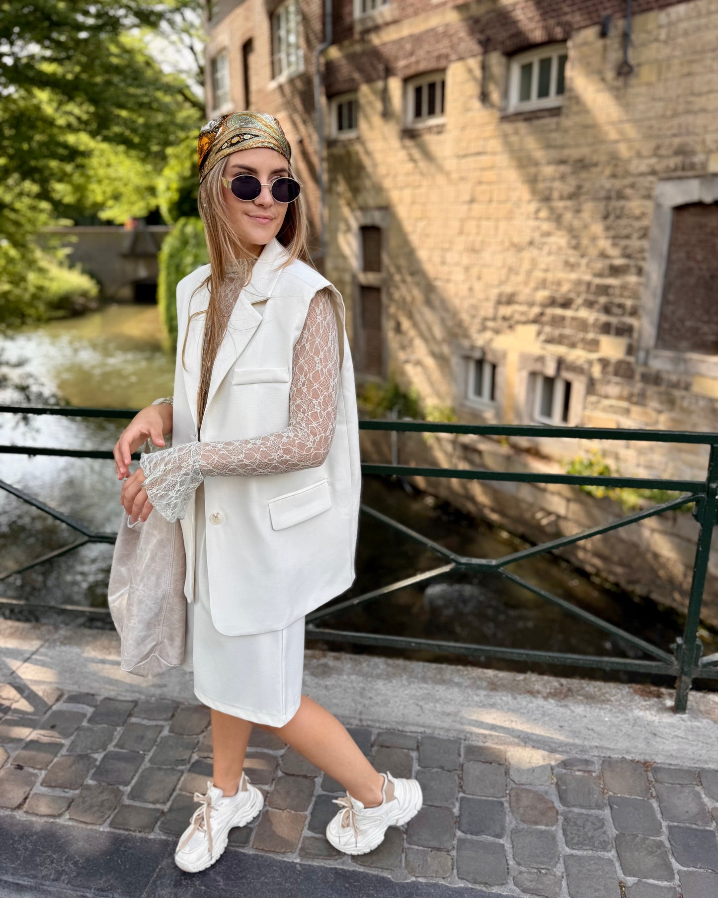 Blazer sans manches couleur écru. Deux fausses poches devant et fente à l’arrière. 
