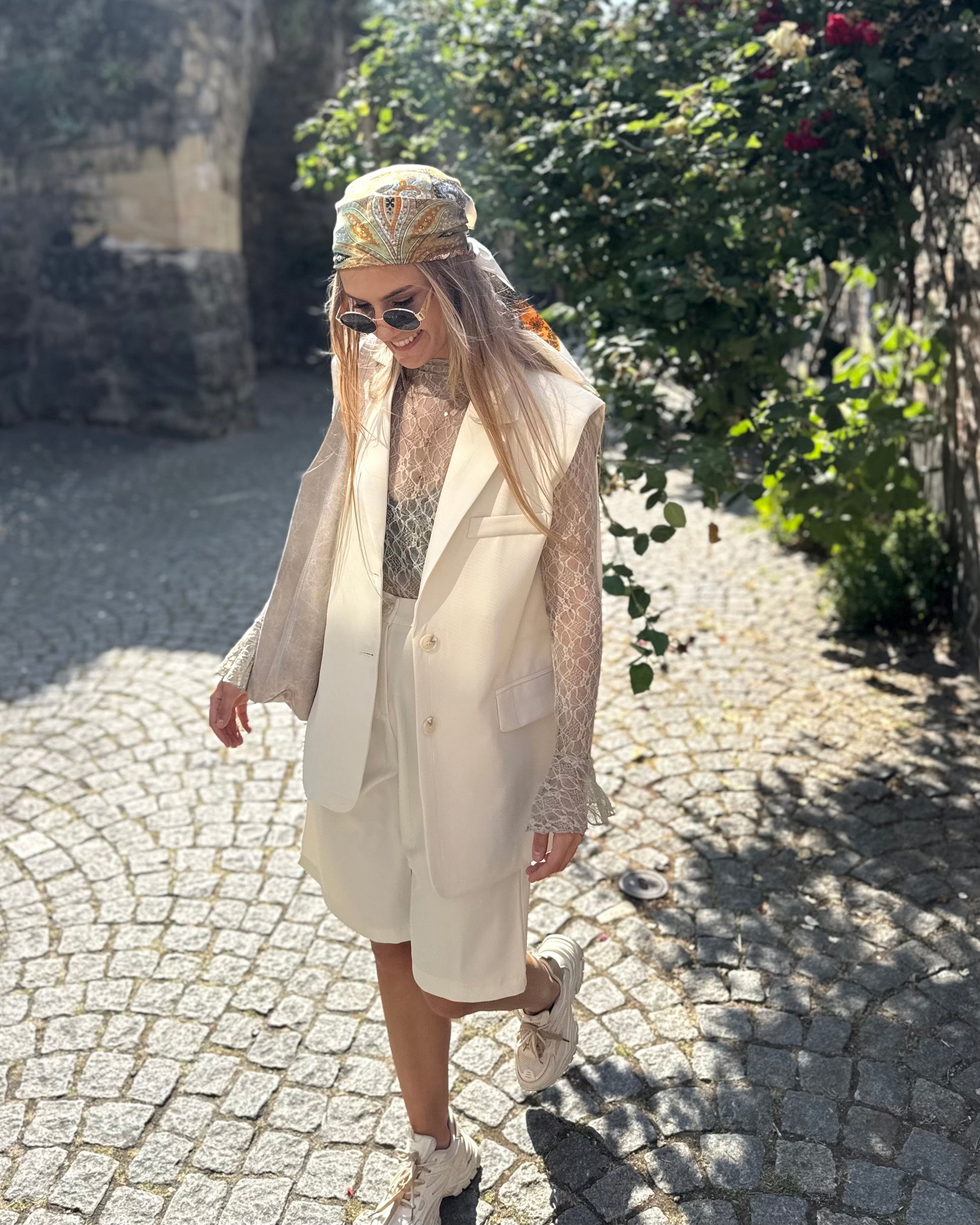 Blazer sans manches couleur écru. Deux fausses poches devant et fente à l’arrière. 