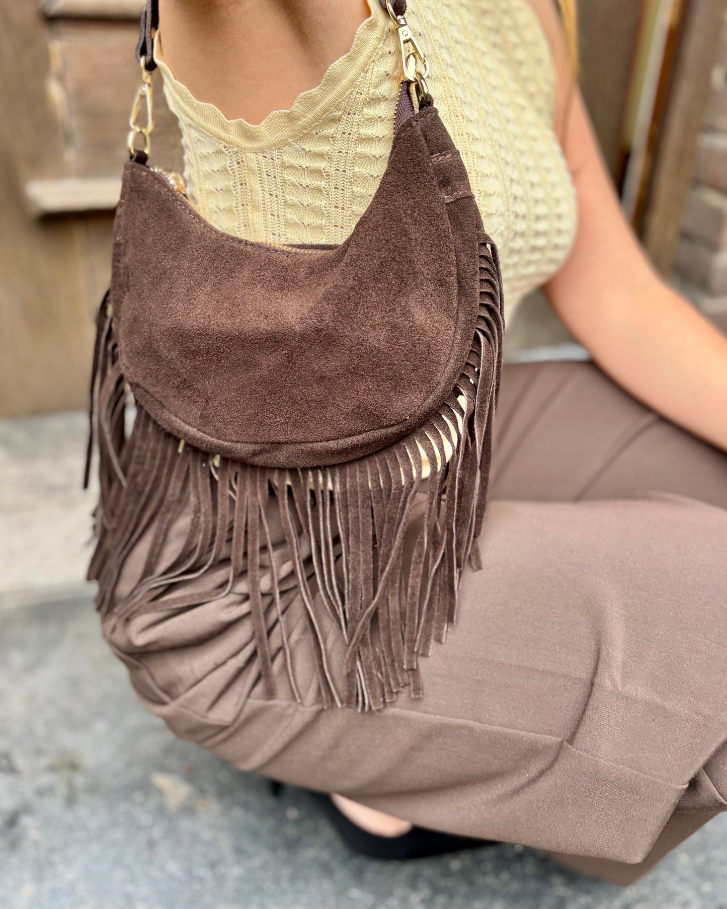 Sac à main en forme demi-lune 100% cuir de vachette. Avec des longues franges sur le bas et une bandoulière ajustable. Finitions dorées. 