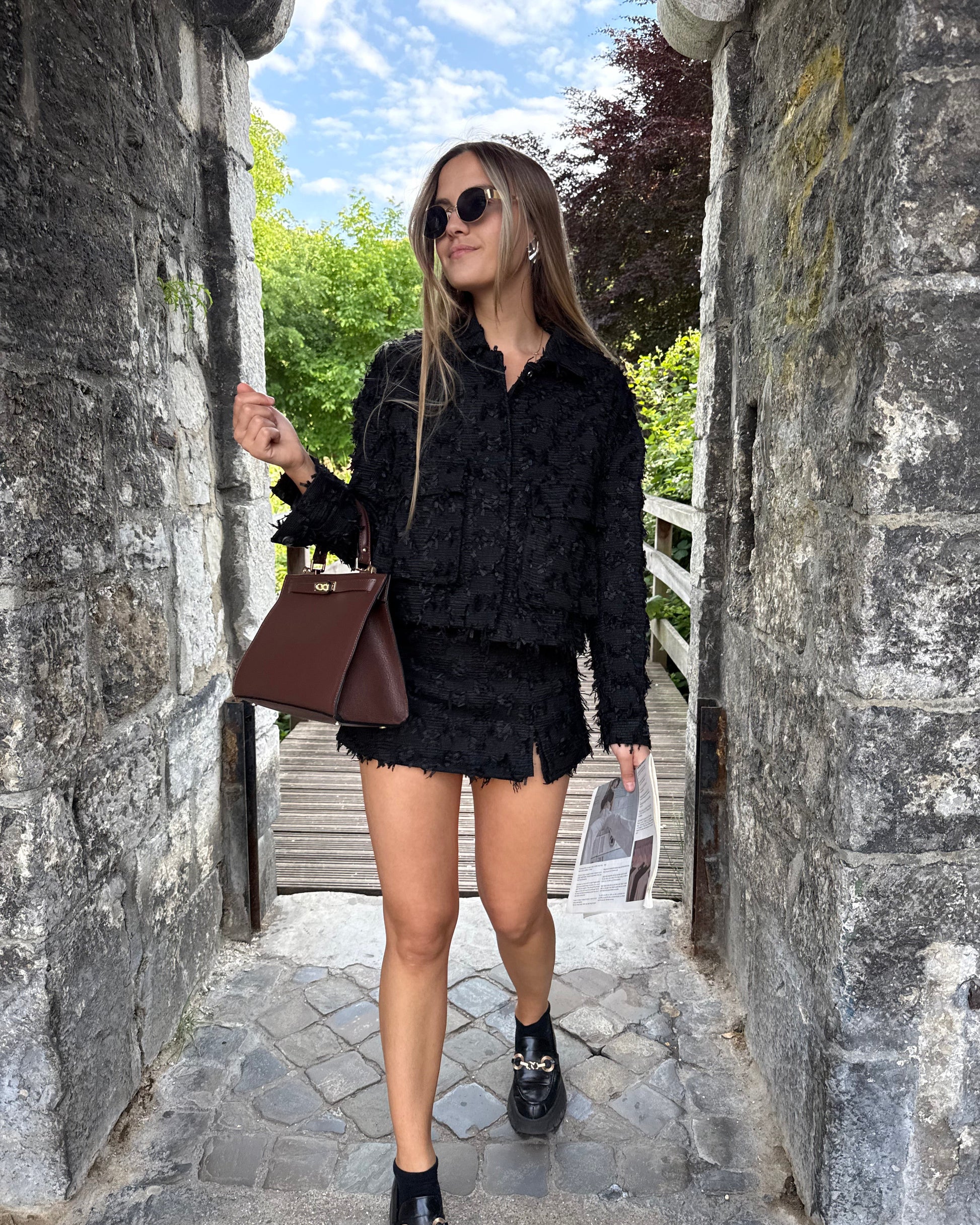 Veste noire en tweed avec deux poches à l’avant. Matière épaisse. Short noir assorti
