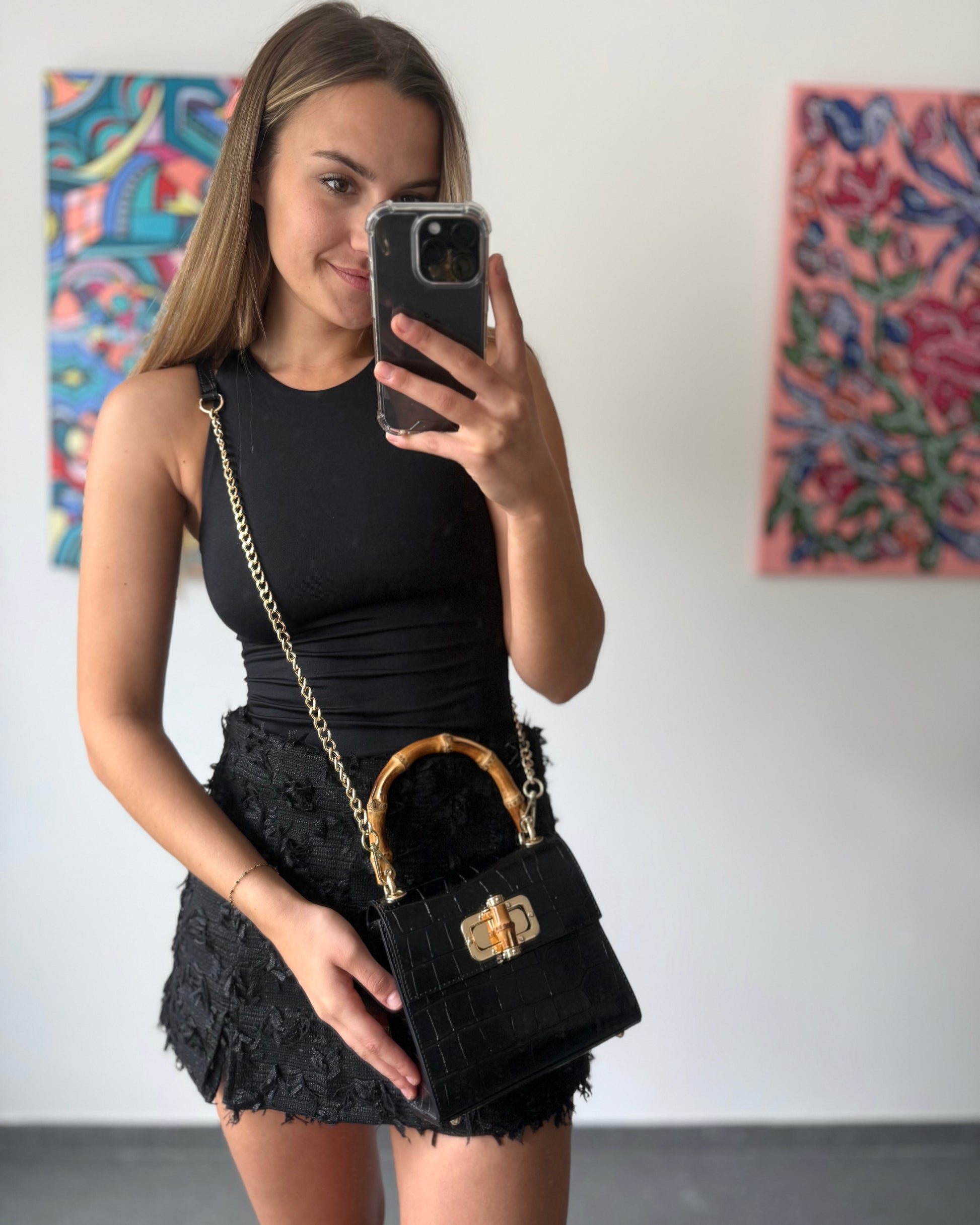 Petit sac à main noir en cuir et poignée en bamboo. Effet croco. Fermoire à l’avant. Sangle disponible. 