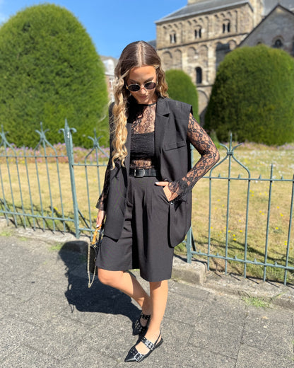 Blazer sans manches couleur noir. Deux fausses poches devant et fente à l’arrière.