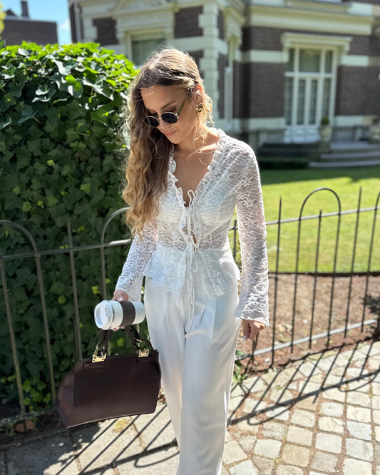 Blouse à dentelle blanche manches longues. S’attache avec deux petites cordelettes. 