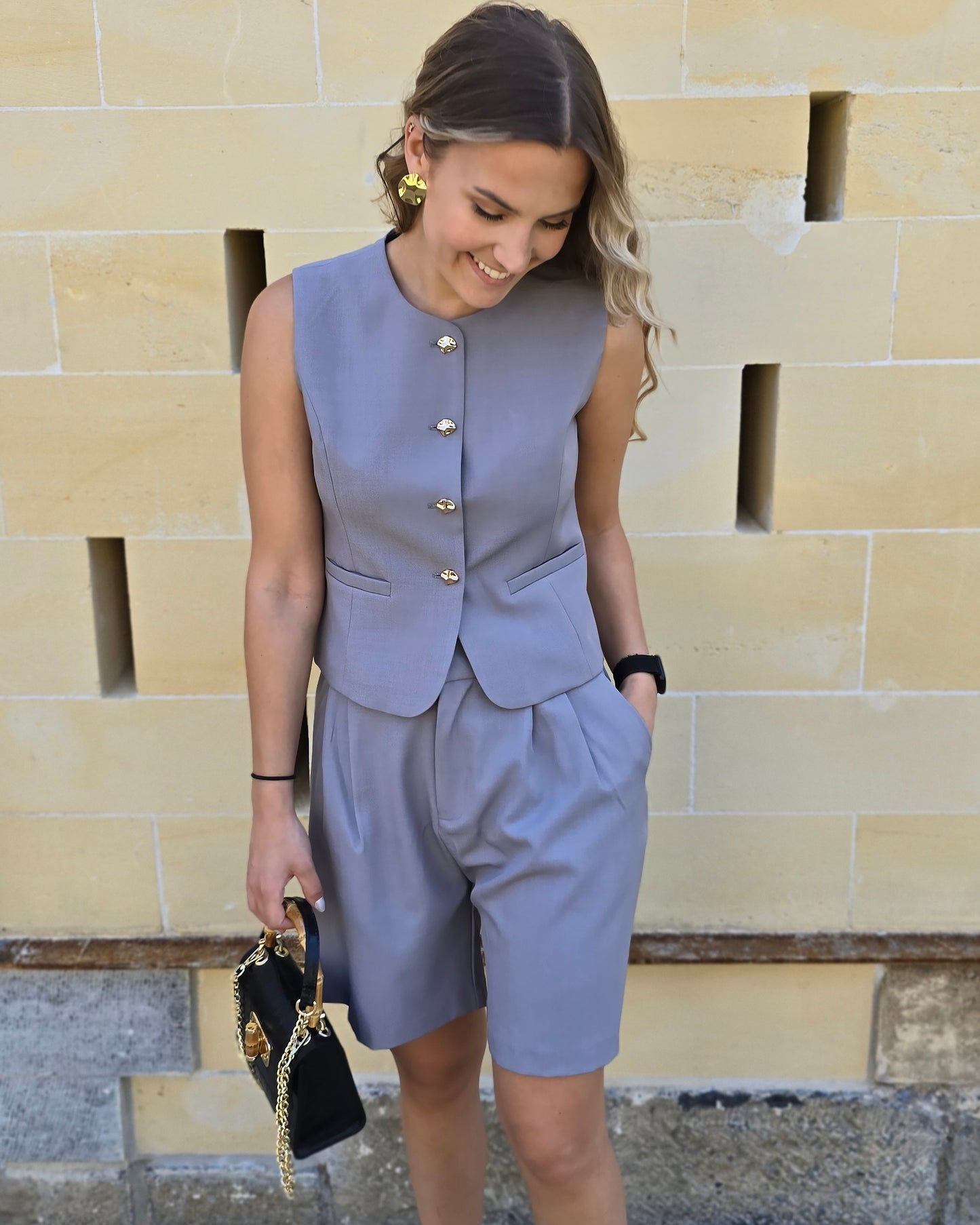 Top tailleur gris foncé avec boutons dorés. Effet cintré et fausses poches sur le devant. 
