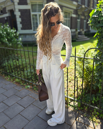 Pantalon blanc large taille haute. Deux poches à l’avant et pinçant pour ceinture. 