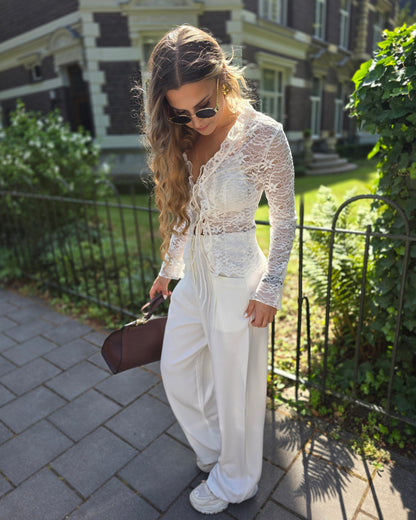 Pantalon blanc large taille haute. Deux poches à l’avant et pinçant pour ceinture. 