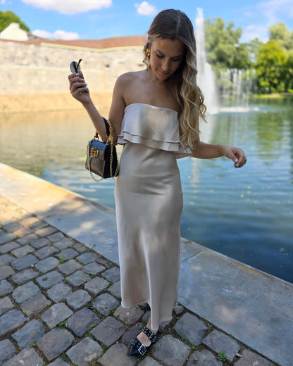 Robe dorée satinée avec volant au buste. Bandé anti-glisse. Longueur maxi.