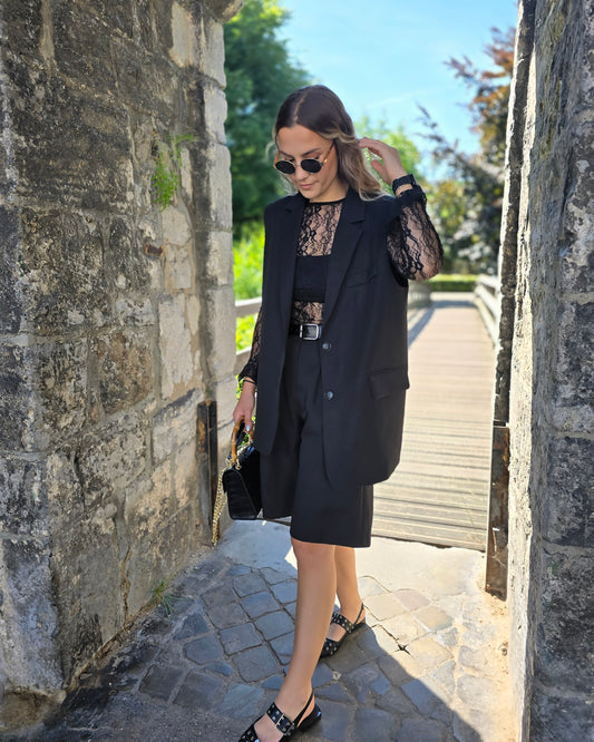 Blazer sans manches couleur noir. Deux fausses poches devant et fente à l’arrière.