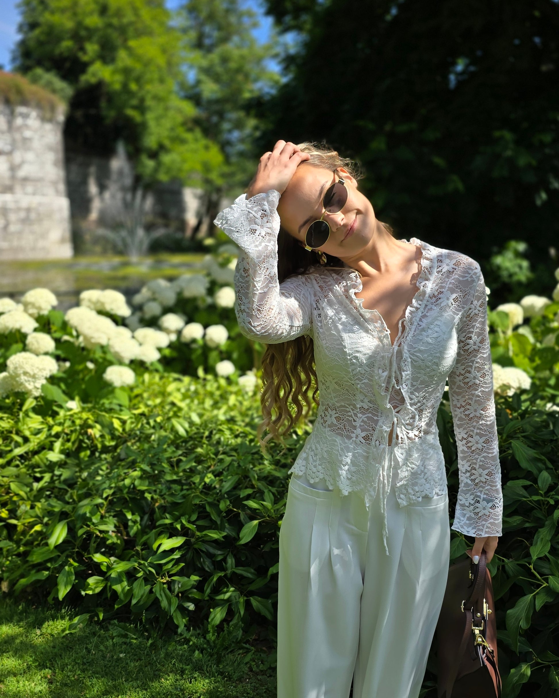 Blouse à dentelle blanche manches longues. S’attache avec deux petites cordelettes. 