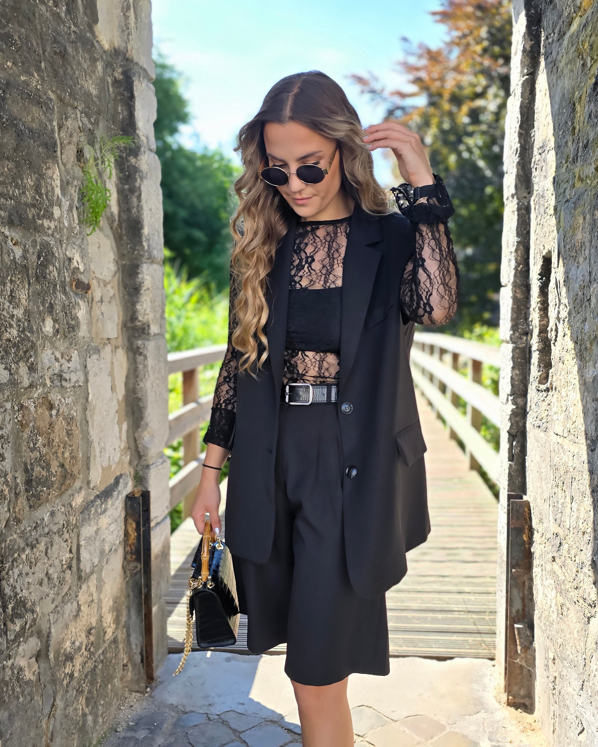 Blazer sans manches couleur noir. Deux fausses poches devant et fente à l’arrière.