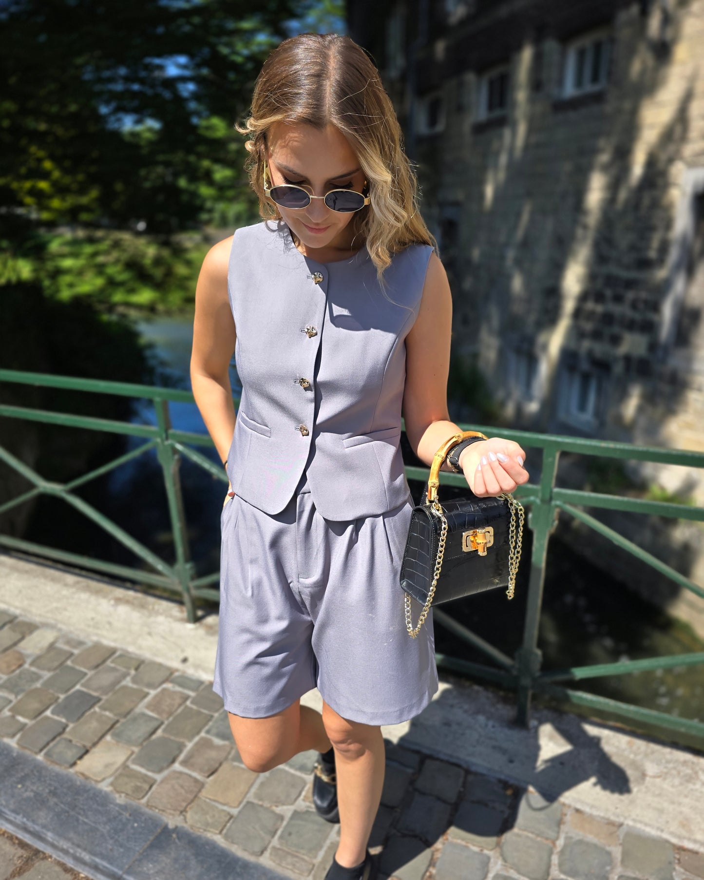 Top tailleur gris foncé avec boutons dorés. Effet cintré et fausses poches sur le devant. 