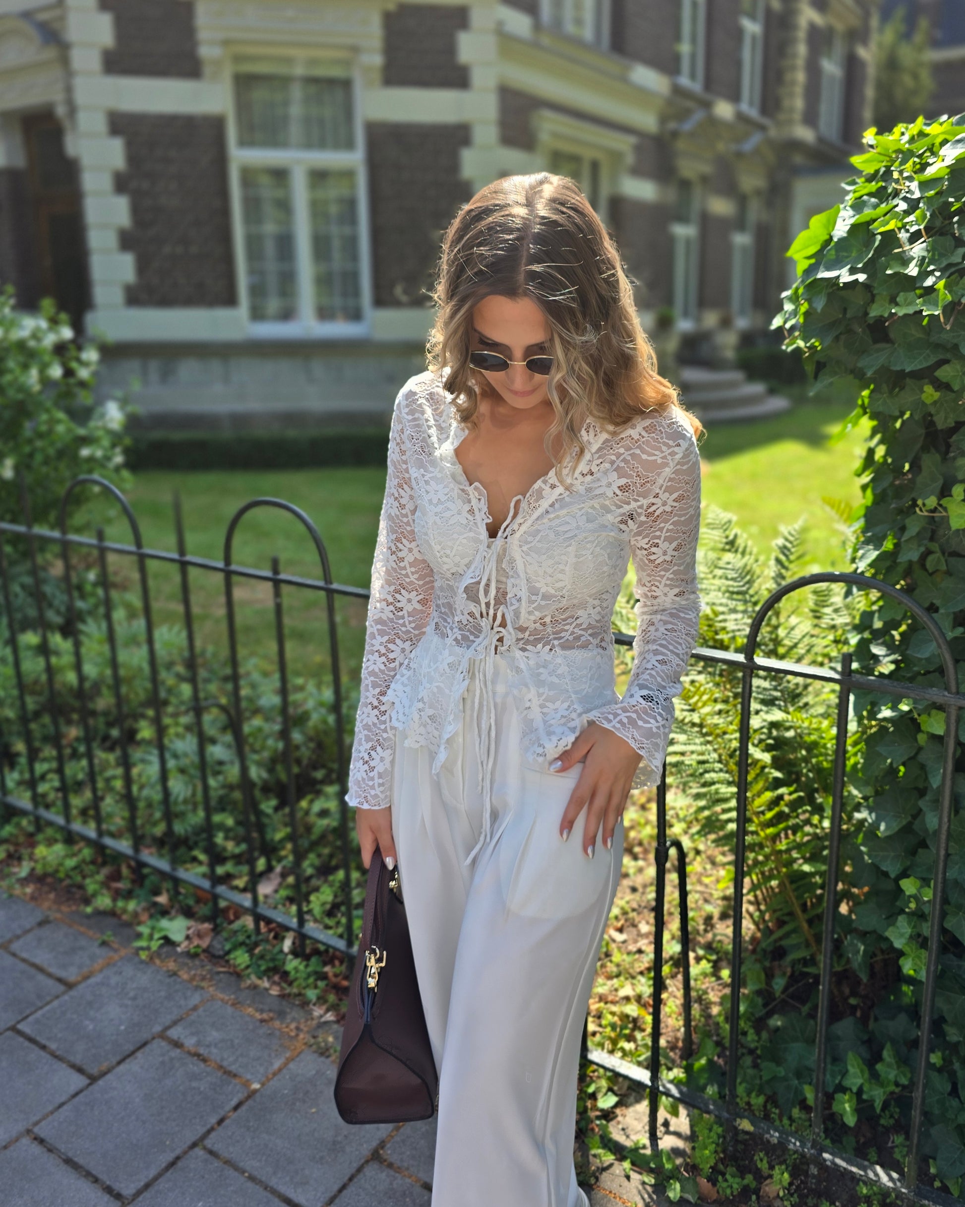 Blouse à dentelle blanche manches longues. S’attache avec deux petites cordelettes. 