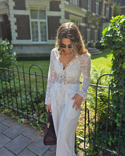 Blouse à dentelle blanche manches longues. S’attache avec deux petites cordelettes. 