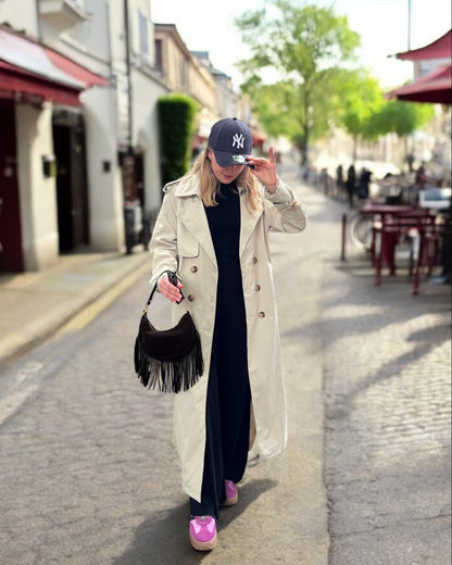 Trench beige coupe longue avec épaules structurées et une ceinture à nouer. Doublé intégralement. 