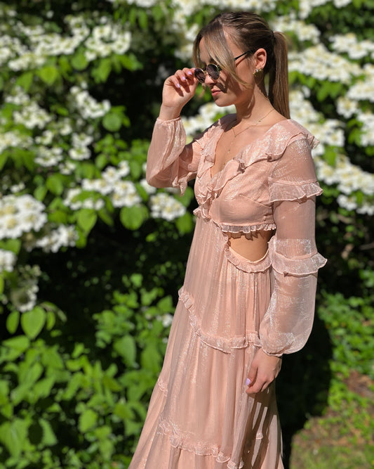 Robe rose longue doublée jusqu’aux cuisses. Décolleté en V avec petits volants. Détails ajourés sur les côtés. 