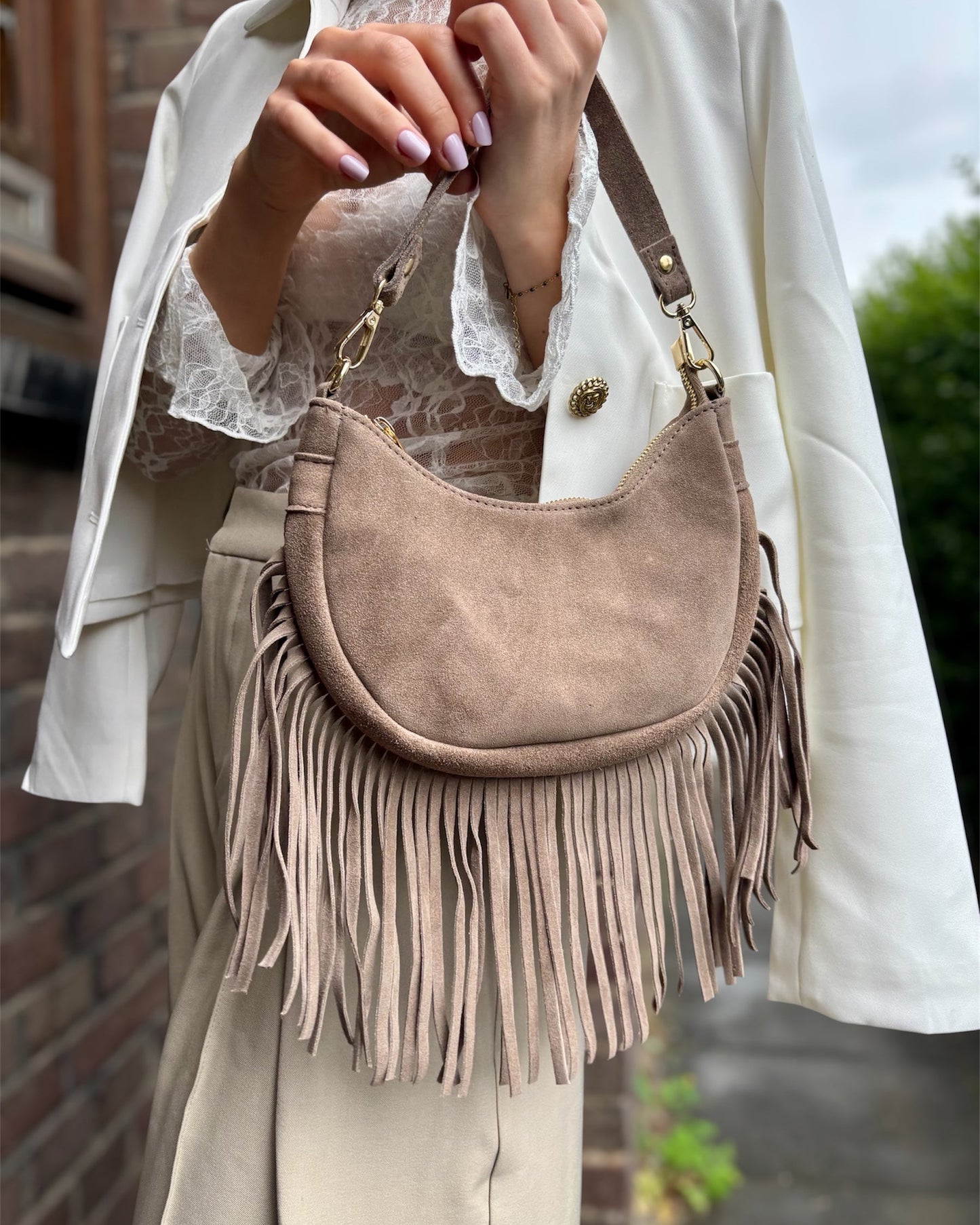 Sac à main en forme demi-lune 100% cuir de vachette. Avec des longues franges sur le bas et une bandoulière ajustable. Finitions dorées. 