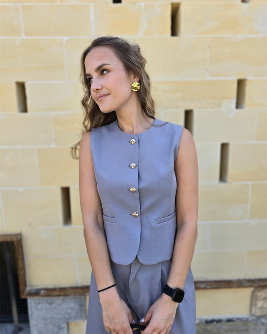 Top tailleur gris foncé avec boutons dorés. Effet cintré et fausses poches sur le devant. 