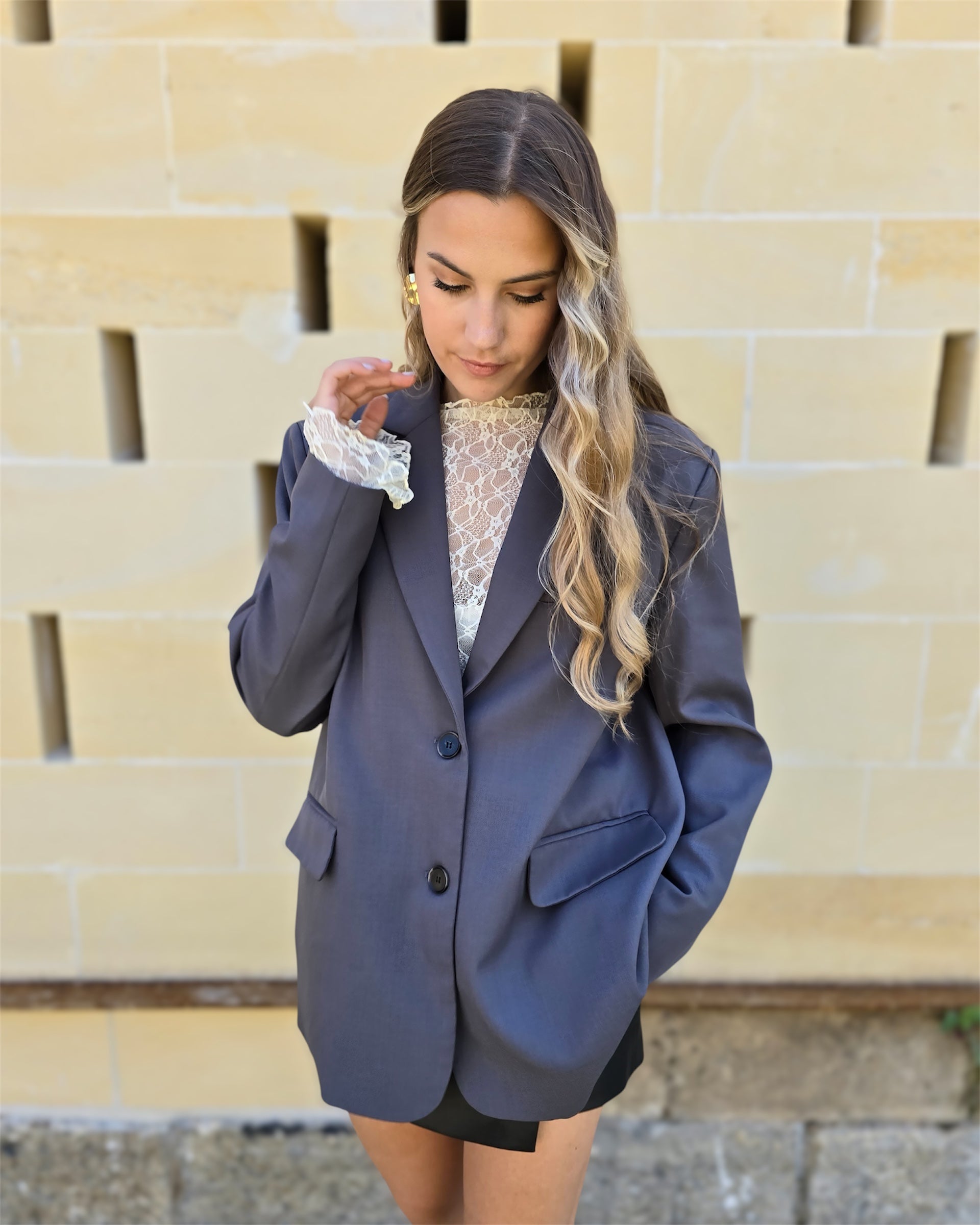 Blazer gris oversize avec ouverture dans le dos. Deux boutons à l’avant et deux fausses poches. 