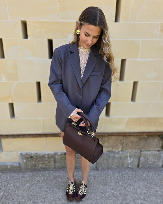 Blazer gris oversize avec ouverture dans le dos. Deux boutons à l’avant et deux fausses poches. 